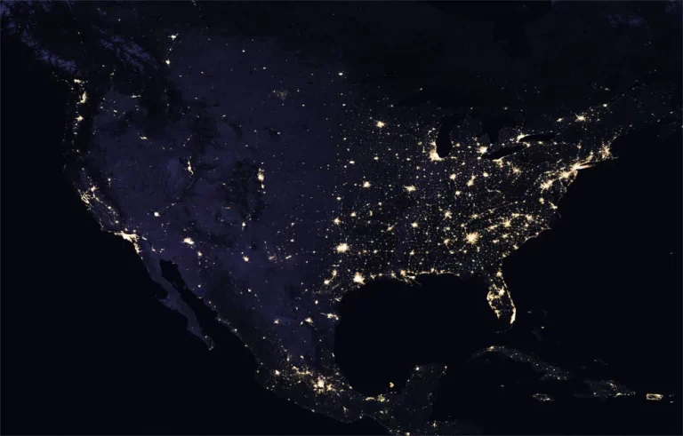 The image shows a night view of the contiguous United States, with city lights illuminating the regions and highlighting the population density patterns across the country.